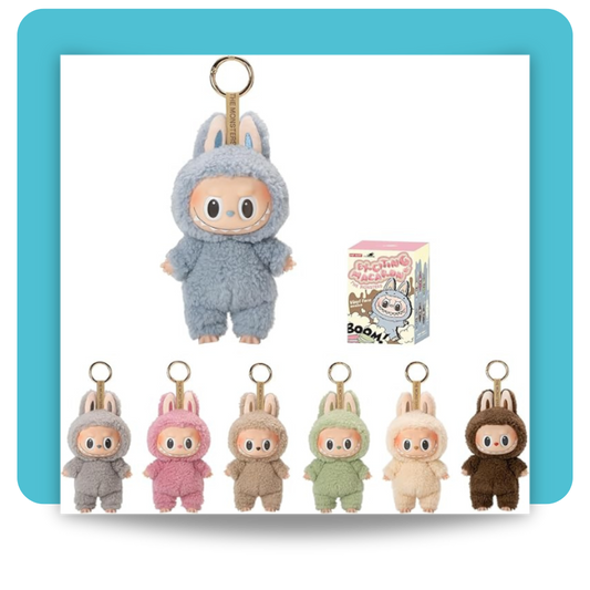 A plush-textured 17 cm keychain figure of Labubu from POP MART’s “Tasty Macarons” series, dressed in a soft pastel-blue onesie with bunny ears and a glossy vinyl face showcasing Labubu’s signature wide eyes and toothy grin, mounted on a gold-tone metal keyring alongside its pastel-themed blind-box packaging featuring whimsical macaron-inspired illustrations