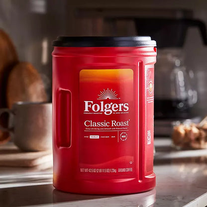 Folgers Classic Roast Ground Coffee 43.5 oz canister on kitchen counter with medium roast label and black lid

